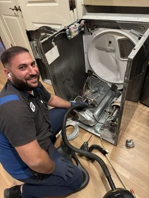 Clothes dryer drum roller vacuuming and maintenance service by technician